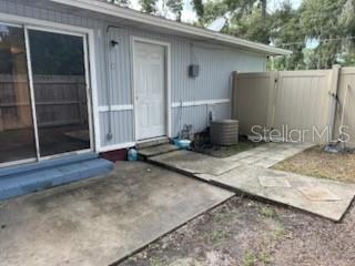 A concrete patio leads to a white door and sliding glass door on a house exterior — 1820 SE 40TH STREET ROAD, OCALA, FL