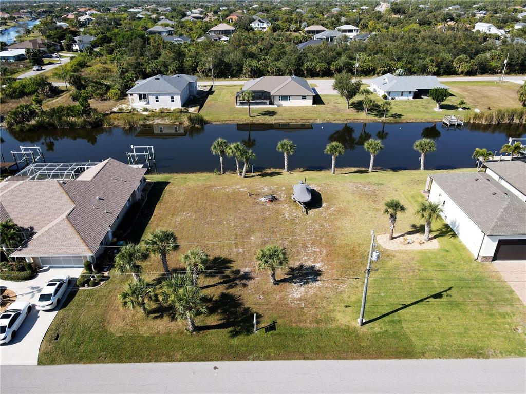 An aerial view shows a vacant residential lot situated between two houses along a canal — 9514 SNAPPER CIRCLE, PORT CHARLOTTE, FL