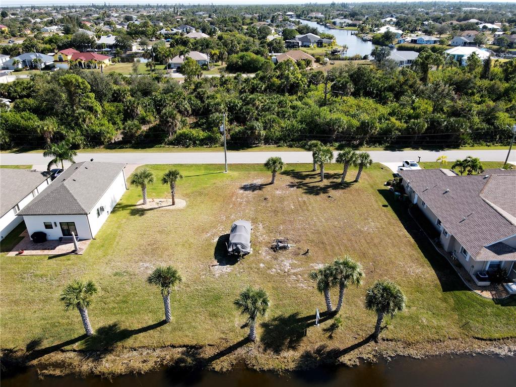 An aerial view shows a vacant residential lot situated between two houses along a canal — 9514 SNAPPER CIRCLE, PORT CHARLOTTE, FL