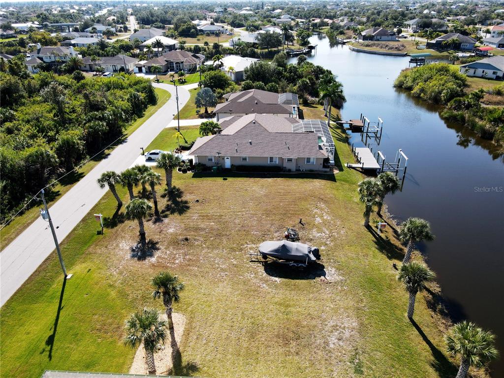 An aerial view shows a vacant waterfront lot with a boat trailer and palm trees — 9514 SNAPPER CIRCLE, PORT CHARLOTTE, FL
