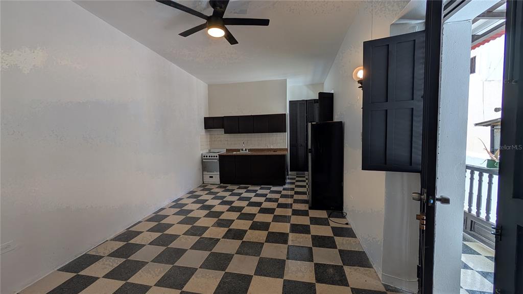 A kitchen area features dark cabinets, a checkered floor, and a door opening to a balcony — 153 SOL ST. UNIT 8, SAN JUAN, PR