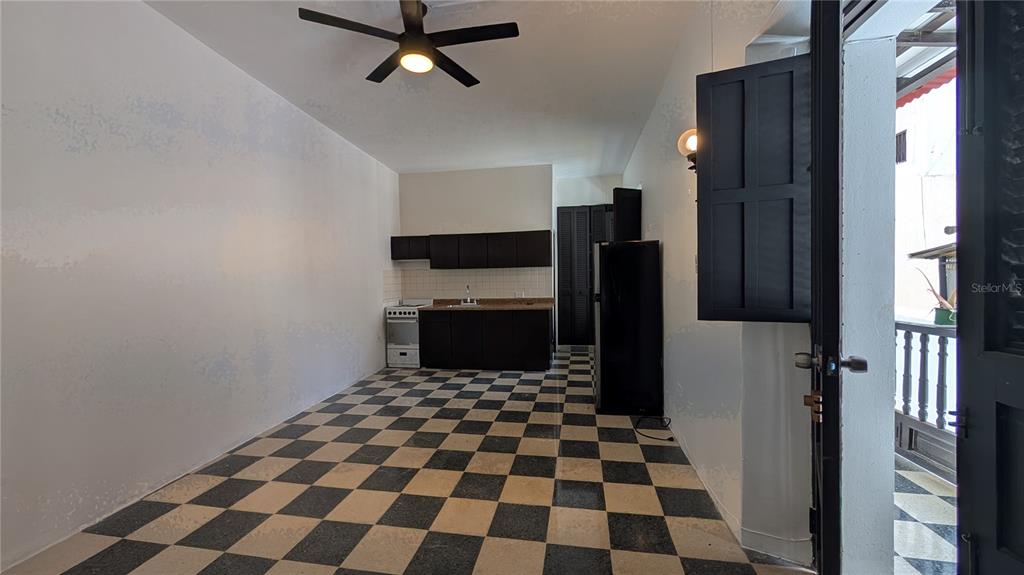 A kitchen with dark cabinets and a checkered floor opens to an outdoor balcony — 153 SOL ST. UNIT 8, SAN JUAN, PR