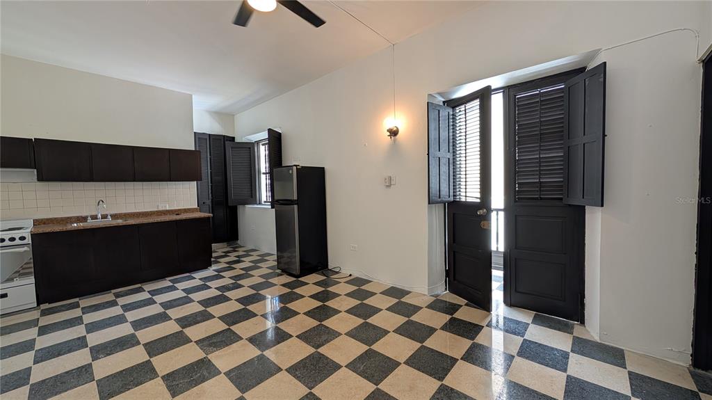 A kitchen with dark cabinets, a checkered floor, and a door opening to a balcony — 153 SOL ST. UNIT 8, SAN JUAN, PR
