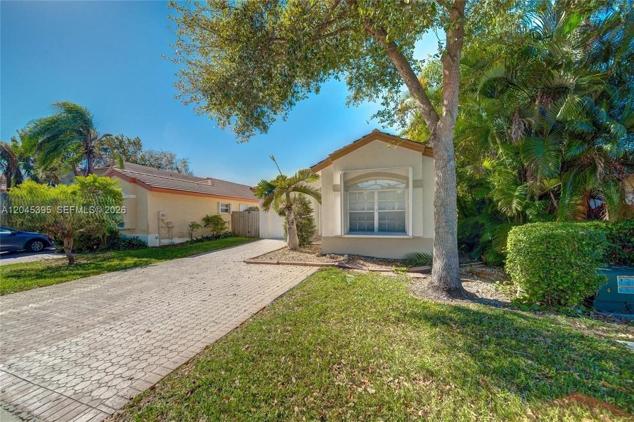 A single-story house features a paved driveway, a front lawn, and mature trees — 2924 NW 99th Pl, Doral FL 33172, DORAL, FL