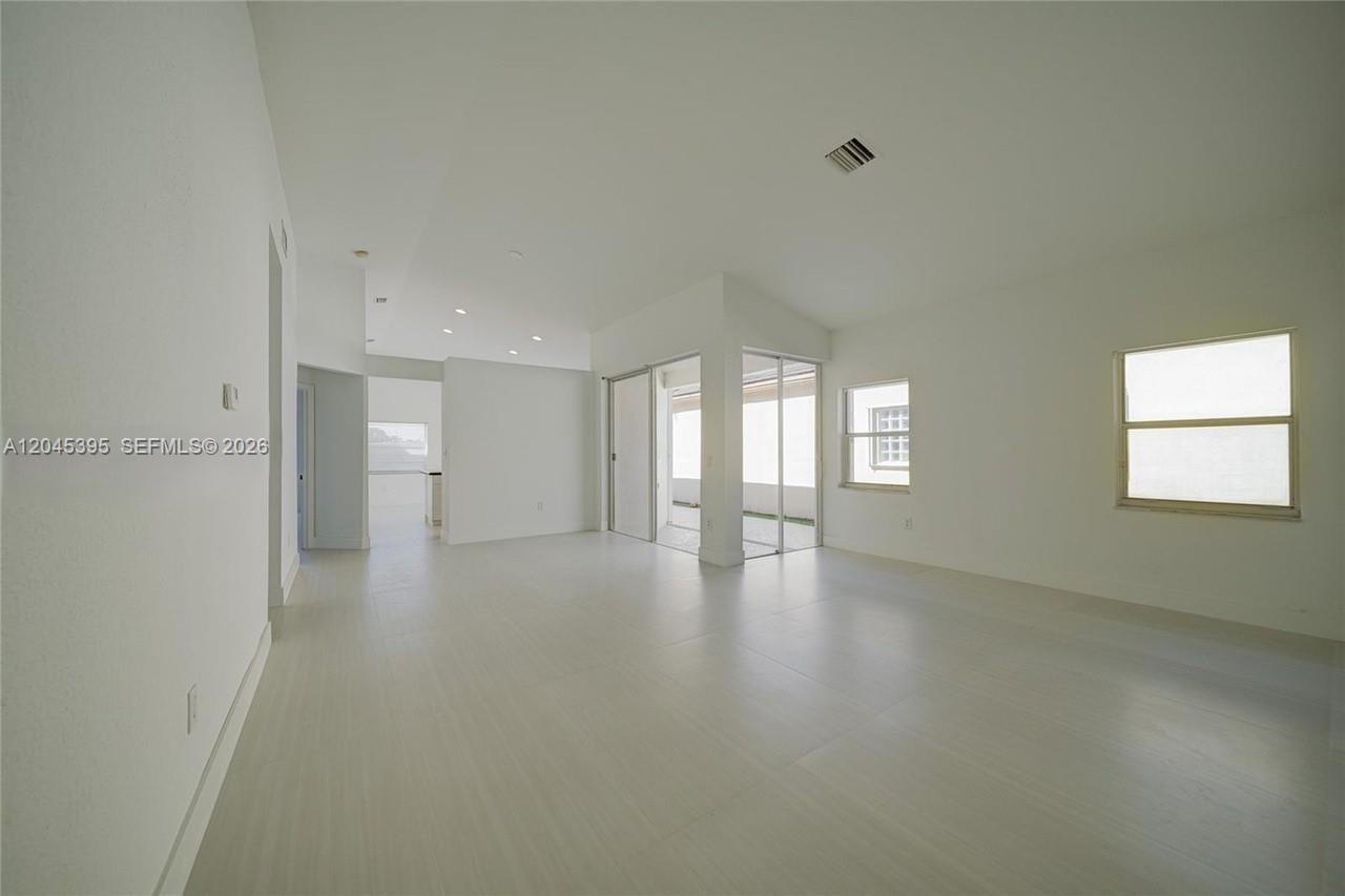 A bright, empty living room features white walls, light-colored tile flooring, and sliding glass doors — 2924 NW 99th Pl, Doral FL 33172, DORAL, FL