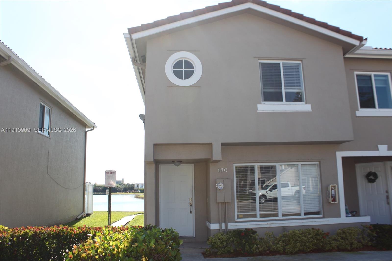 A two-story tan townhouse exterior features a circular window, a white front door, and landscaping — 180 Riviera Cir # 5, Weston FL 33326, WESTON, FL