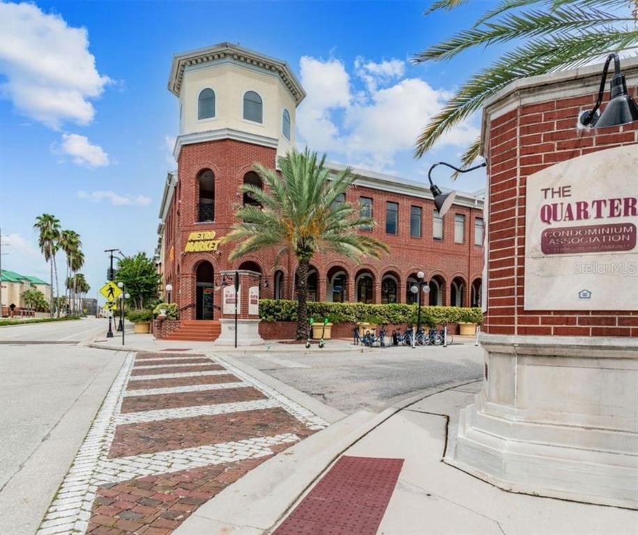 A brick building with a corner tower and a sign for The Quarter Condominium Association — 1880 E PALM AVENUE, TAMPA, FL
