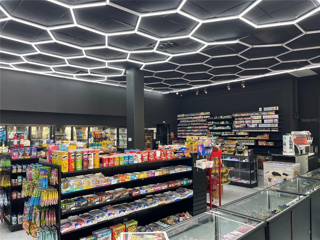 A retail store interior features black walls, shelving units, and a hexagonal LED ceiling grid — 1880 E PALM AVENUE, TAMPA, FL