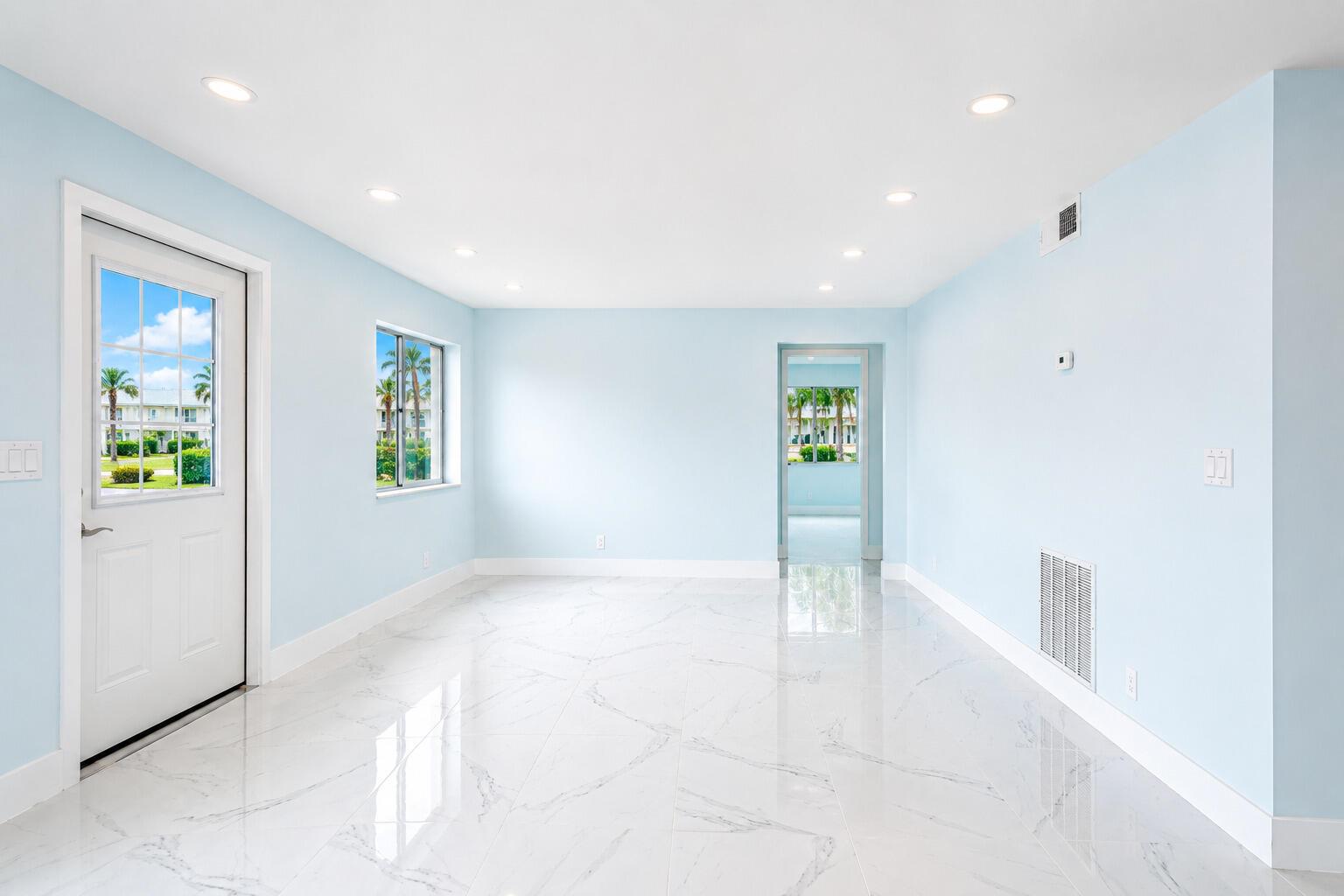 An empty room with light blue walls, white marble-look tile flooring, and recessed ceiling lights — 303 Knotty Pine Circle # 1, FL 33463, FL
