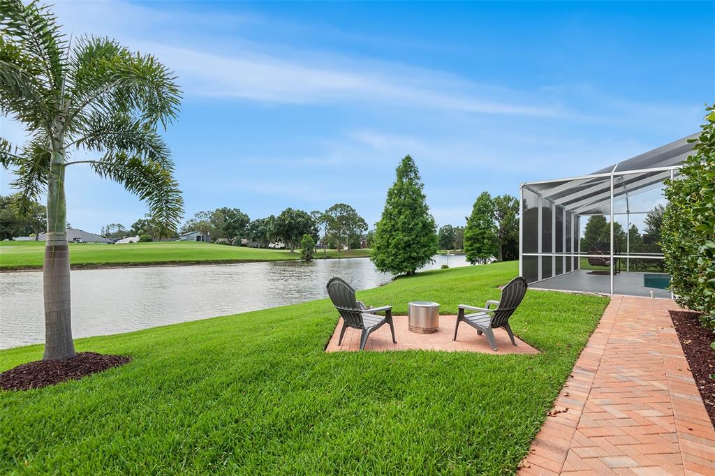 A backyard patio with two chairs and a fire pit overlooks a lake and golf course — 4040 PALMA CEIA CIRCLE, WINTER HAVEN, FL