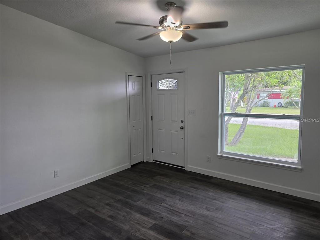 A room with white walls, dark wood-look flooring, a ceiling fan, and an exterior door — 5660 PECOS STREET, ORLANDO, FL