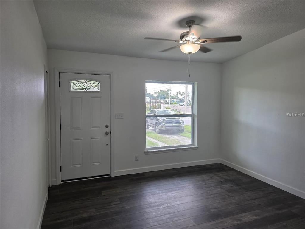 A room with white walls, dark wood-look flooring, a ceiling fan, and a front door — 5660 PECOS STREET, ORLANDO, FL