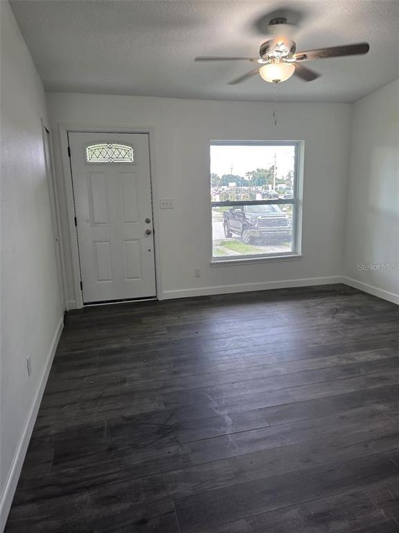 A room with dark wood-look flooring, a white front door, and a ceiling fan — 5660 PECOS STREET, ORLANDO, FL