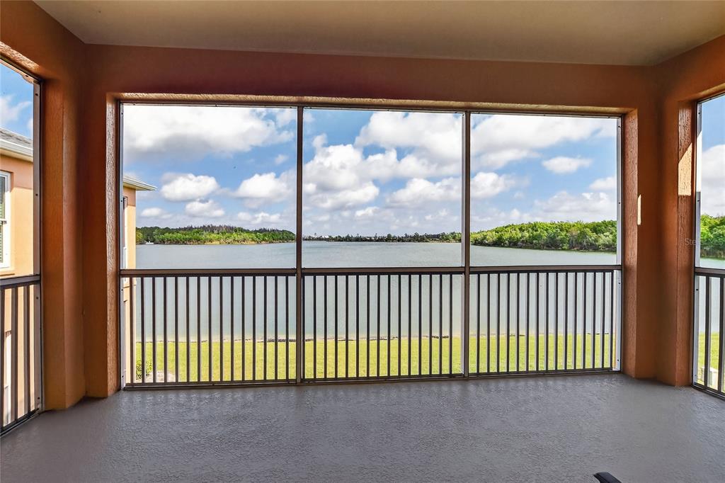 A screened-in balcony overlooks a lake with a grassy lawn and trees in the distance — 3933 SERENADE LANE, LAKELAND, FL