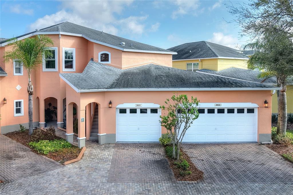 A two-story peach-colored house features a two-car garage and a paved driveway — 3933 SERENADE LANE, LAKELAND, FL