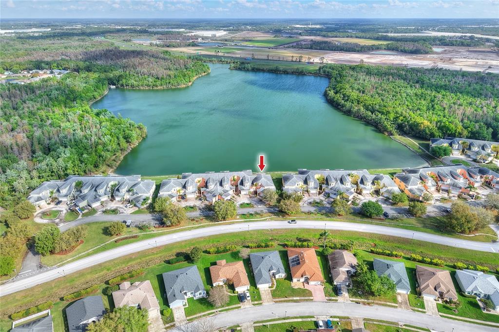 An aerial view shows a residential complex situated along a lake with surrounding greenery — 3933 SERENADE LANE, LAKELAND, FL