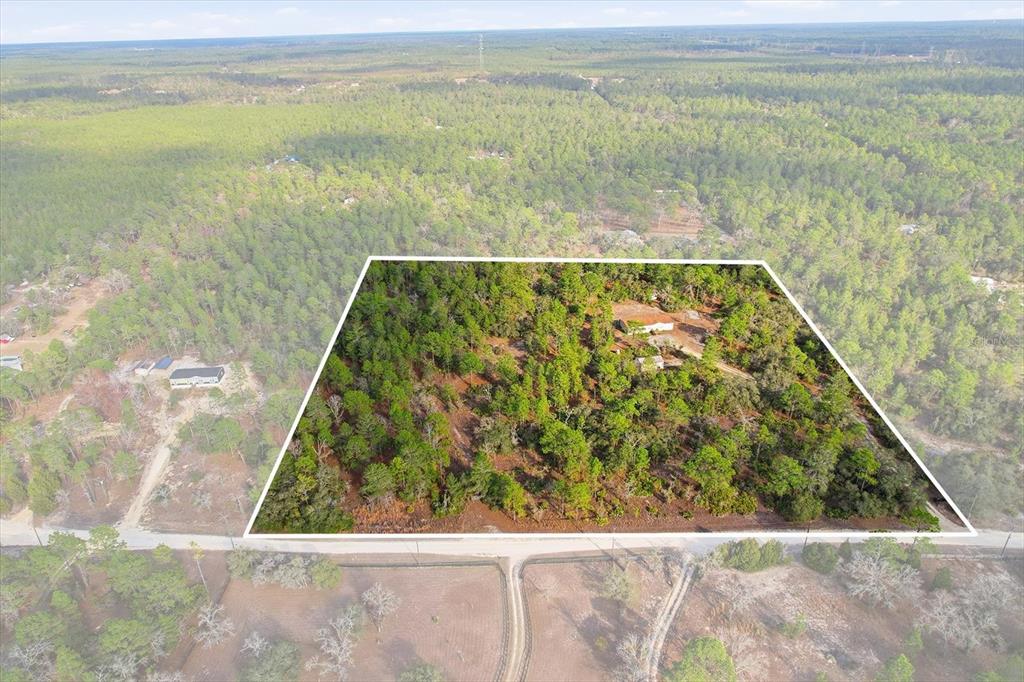 An aerial view shows a wooded residential lot outlined in white with a house inside — 7545 N DAMASCUS AVENUE, DUNNELLON, FL