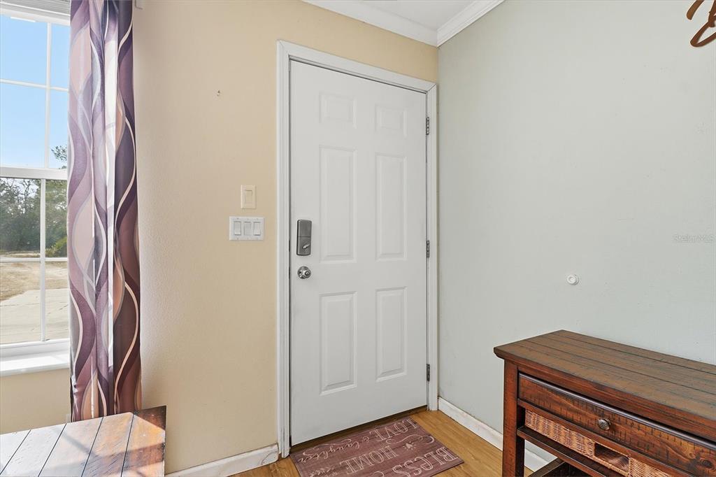 An interior view shows a white front door with a smart lock and a doormat — 7545 N DAMASCUS AVENUE, DUNNELLON, FL