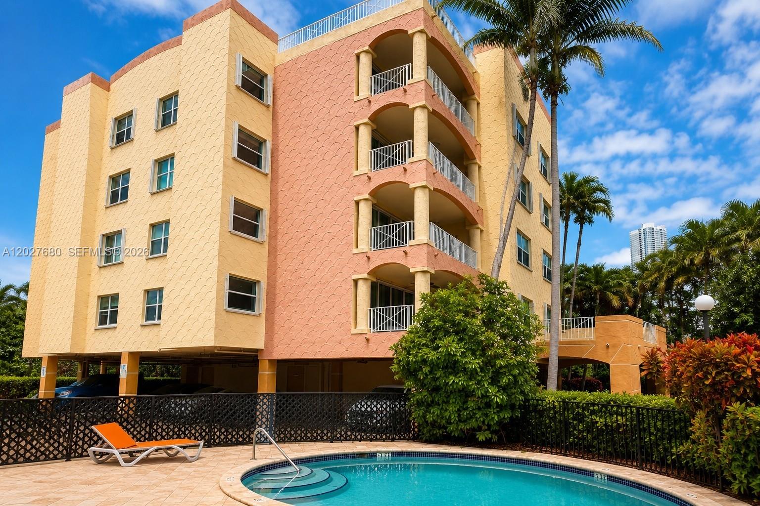 A multi-story peach-colored apartment building stands behind a swimming pool with a lounge chair — 1834 Brickell Ave # 43, Miami FL 33129, MIAMI, FL
