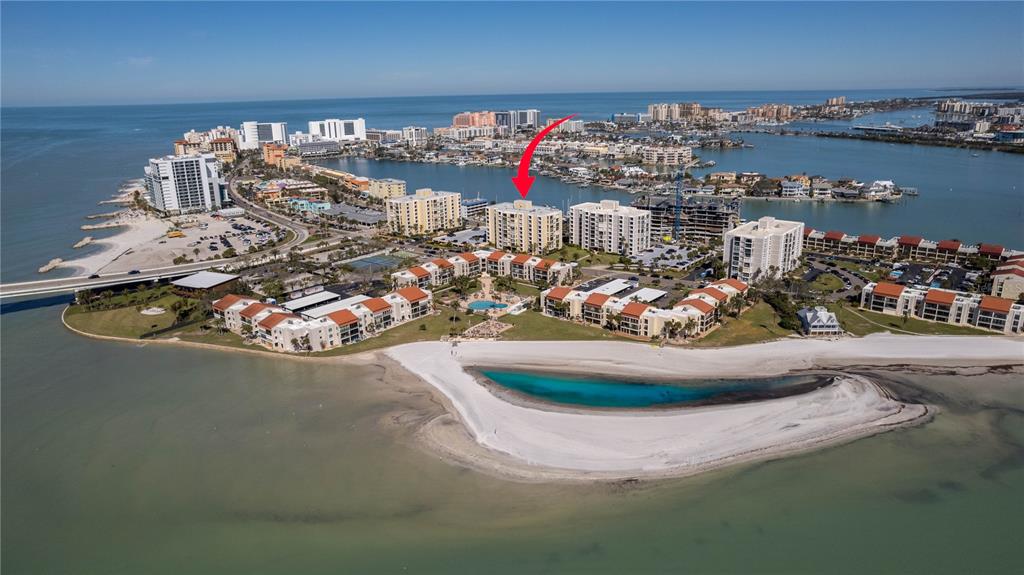 A wide, white sand beach meets the water with a bridge visible in the distance — 830 S GULFVIEW BOULEVARD UNIT 501, CLEARWATER BEACH, FL