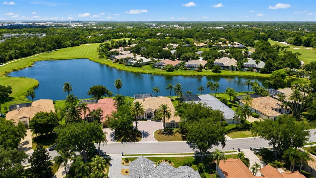 An aerial view shows houses along a lake with a golf course in the background — 7218 MARLOW PLACE, UNIVERSITY PARK, FL