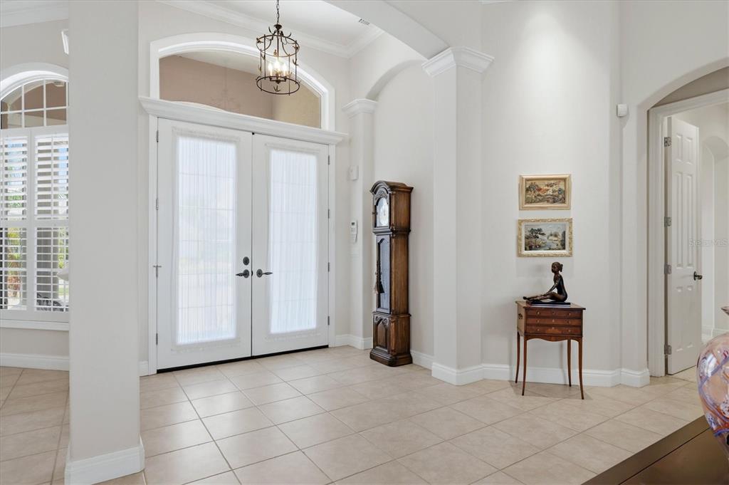 A bright foyer features tile flooring, a grandfather clock, and double front doors with glass — 7218 MARLOW PLACE, UNIVERSITY PARK, FL
