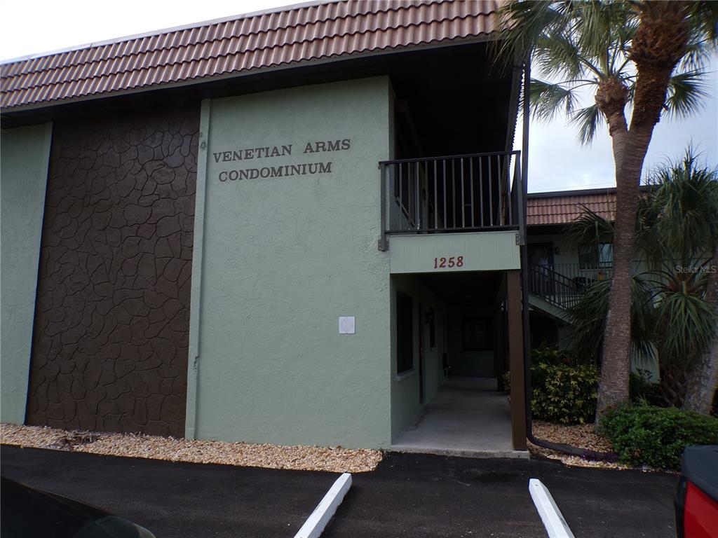 The exterior of a multi-story condominium building features green stucco walls and a brown roof — 1258 BARBARA DRIVE UNIT 106, VENICE, FL