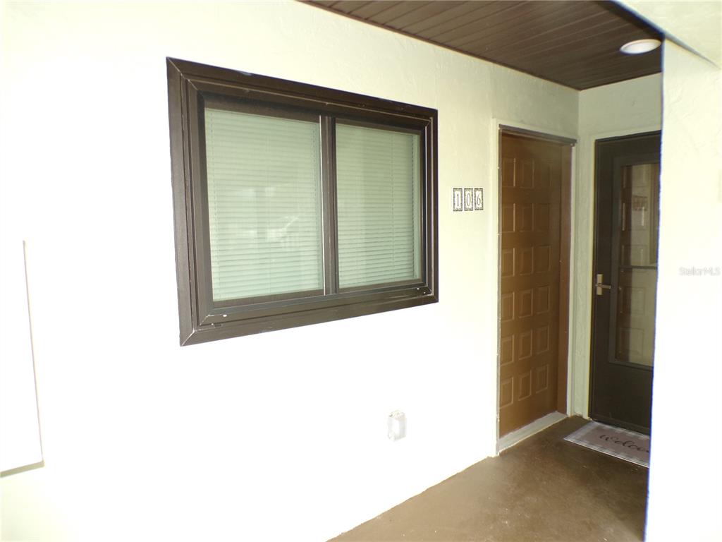 A brown front door and a window with blinds are visible on a covered porch — 1258 BARBARA DRIVE UNIT 106, VENICE, FL
