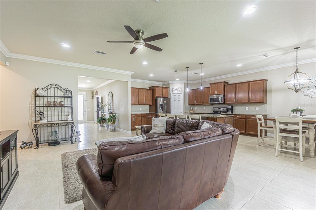 An open-concept living room and kitchen feature tile flooring, brown leather furniture, and wooden cabinetry — 1507 WINDY GAP PLACE, VALRICO, FL