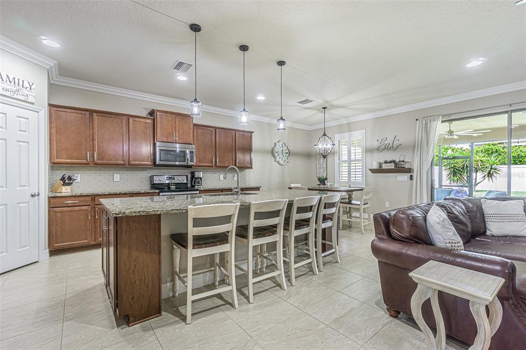 A kitchen with wood cabinets, granite countertops, an island with bar seating, and tile flooring — 1507 WINDY GAP PLACE, VALRICO, FL