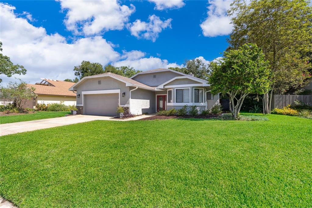 A single-story gray house with a two-car garage and a large front lawn — 4651 TIFFANY WOODS CIRCLE, OVIEDO, FL