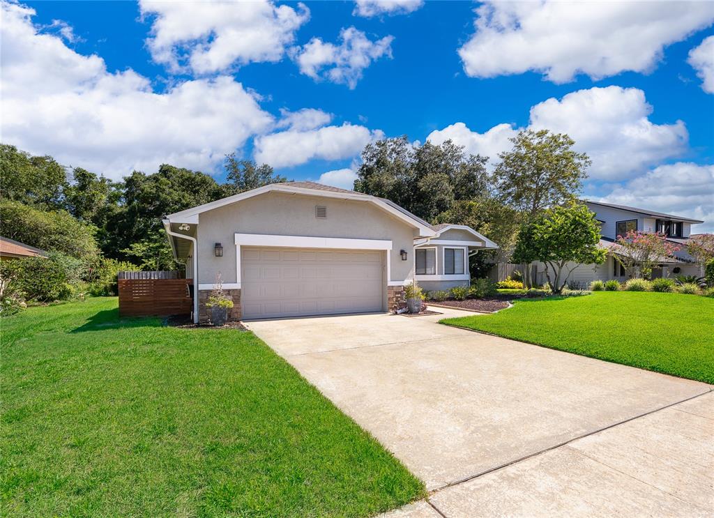 A single-story house with a beige stucco exterior, stone accents, and a two-car garage — 4651 TIFFANY WOODS CIRCLE, OVIEDO, FL