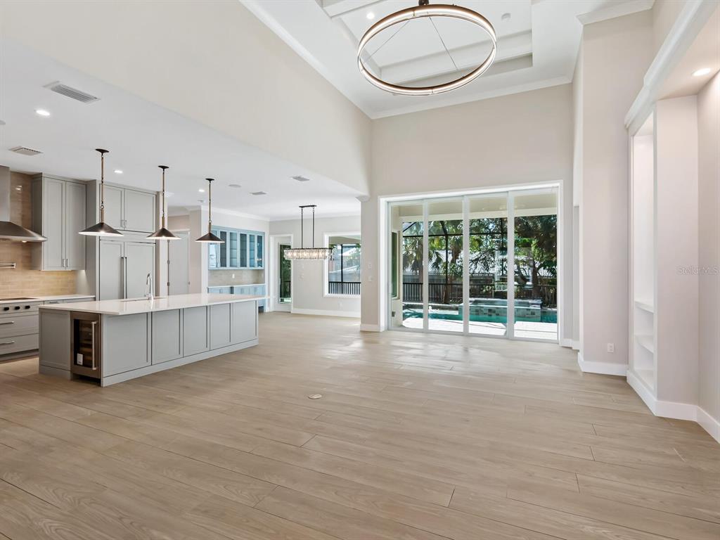 A modern open-concept kitchen and living area with light wood floors and sliding glass doors — 482 E ROYAL FLAMINGO DRIVE, SARASOTA, FL