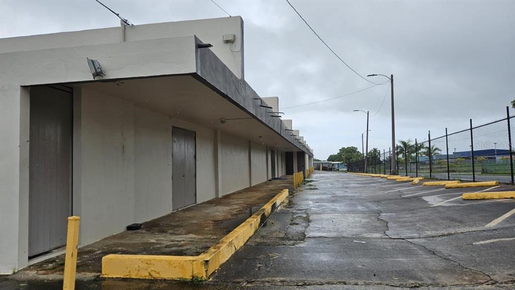 A row of commercial units with a covered walkway and an adjacent paved parking lot — 2 CALLE 5, FAJARDO, PR