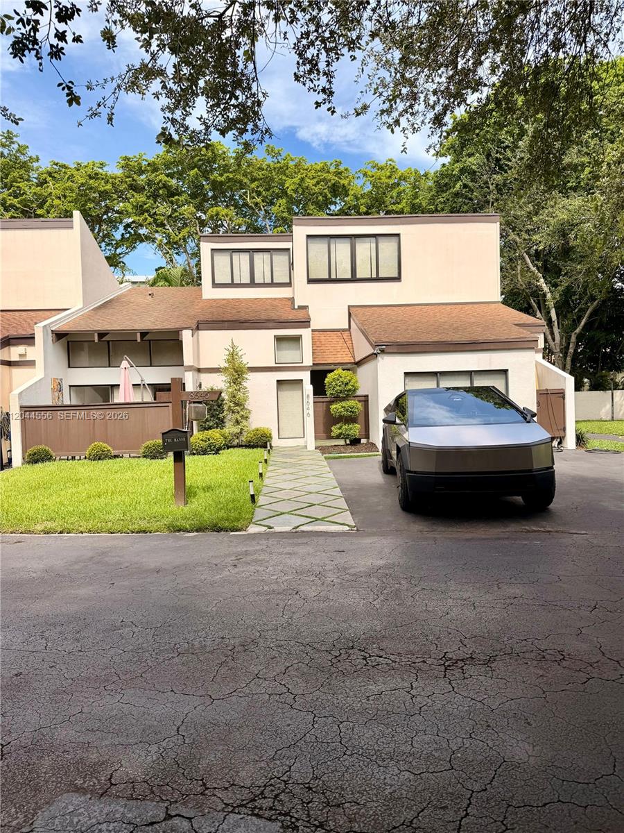 A modern angular vehicle is parked in the driveway of a multi-level suburban home — 8646 SW 94th St, Miami FL 33156, MIAMI, FL
