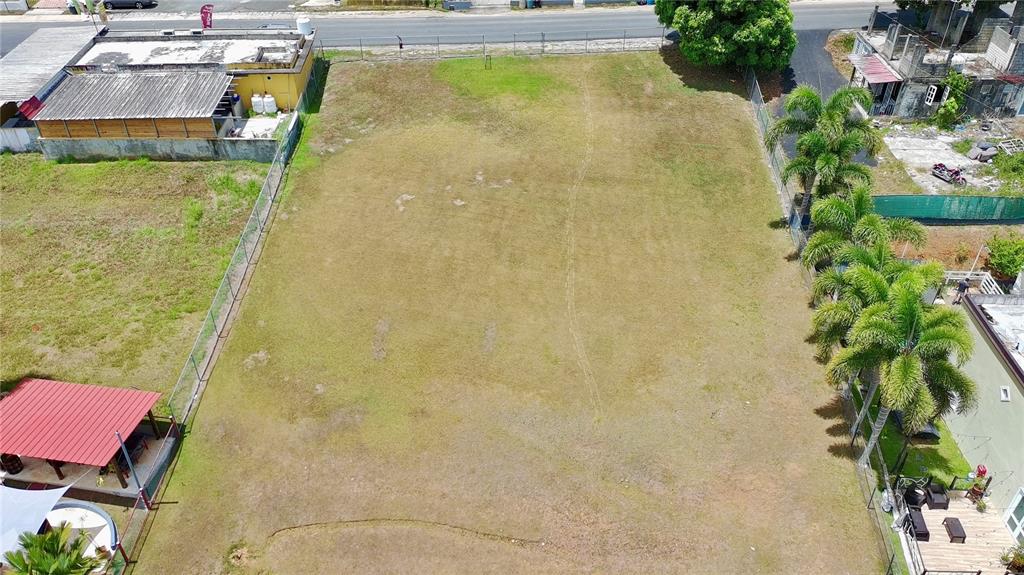 An aerial view shows a rectangular, grassy vacant lot bordered by fences and neighboring properties — CARR 662, MOROVIS, PR