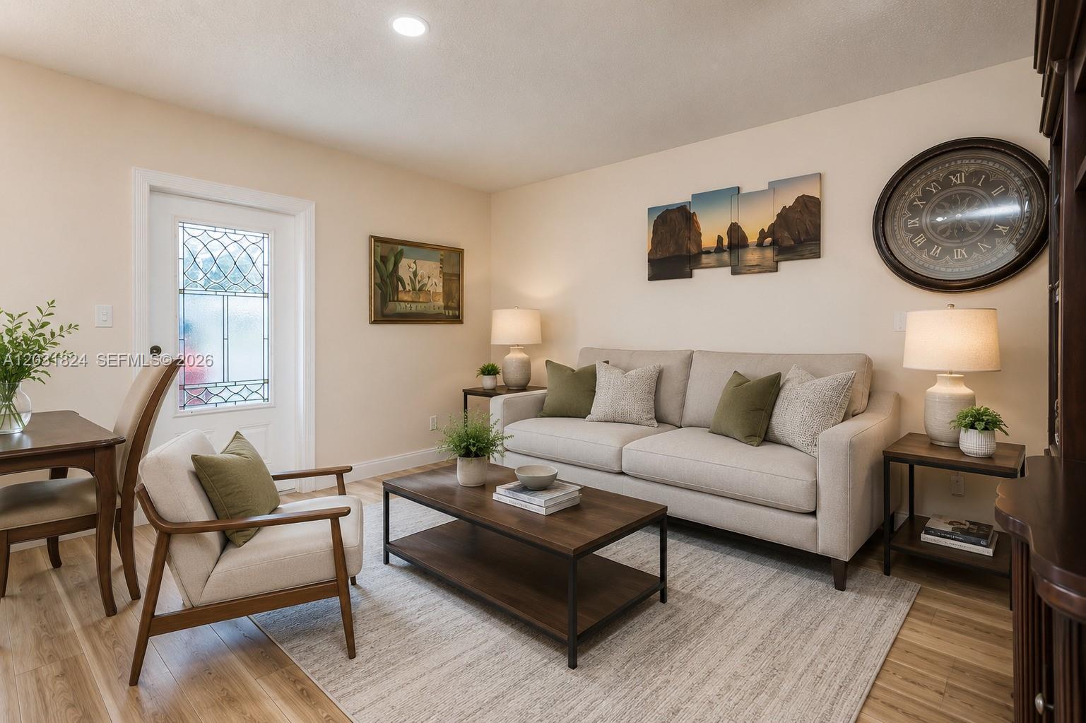 A living room features a beige sofa, a wooden coffee table, and a large wall clock — 630 NW 199th St, Miami Gardens FL 33169, MIAMI GARDENS, FL