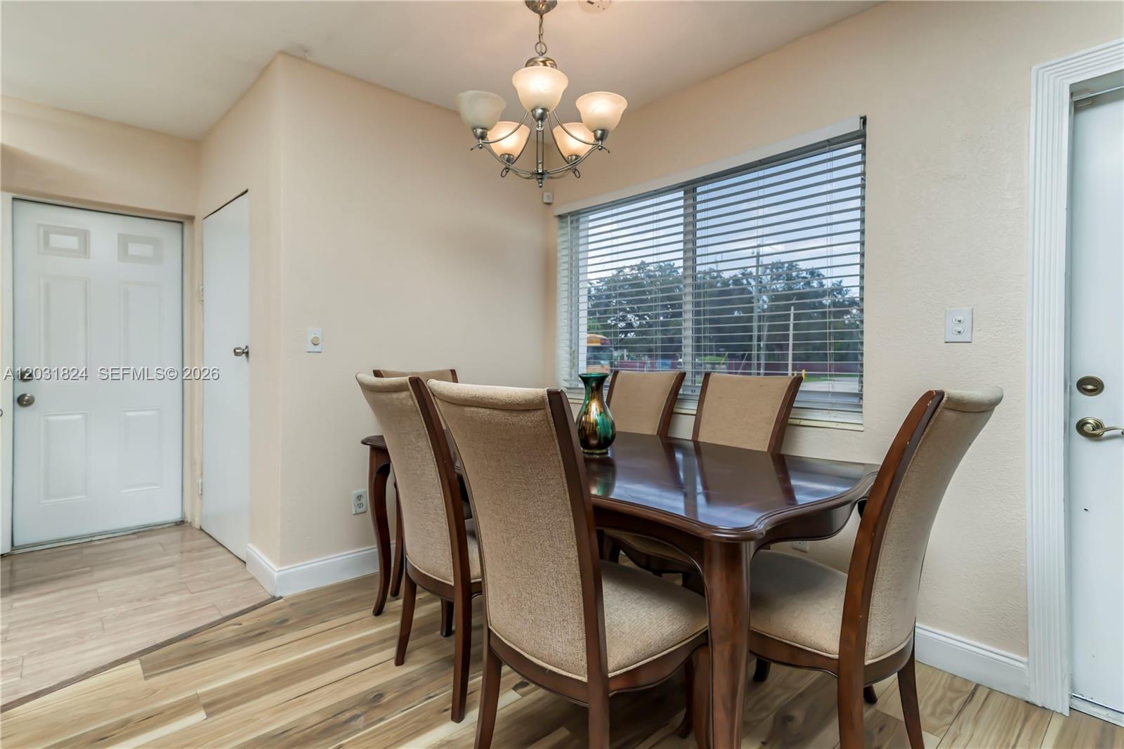 A dining room features a wooden table with six upholstered chairs under a chandelier — 630 NW 199th St, Miami Gardens FL 33169, MIAMI GARDENS, FL