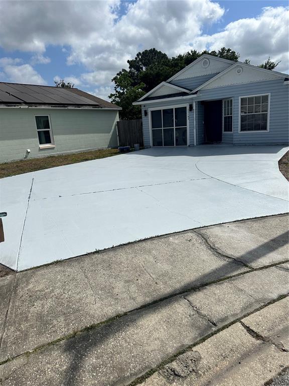 A light blue house features a freshly painted light gray driveway and a screened-in garage — 11165 EINBENDER ROAD, ORLANDO, FL