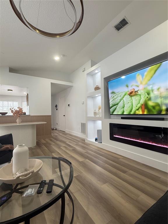 A living room features wood-look flooring, a built-in fireplace, recessed shelving, and a modern chandelier — 11165 EINBENDER ROAD, ORLANDO, FL
