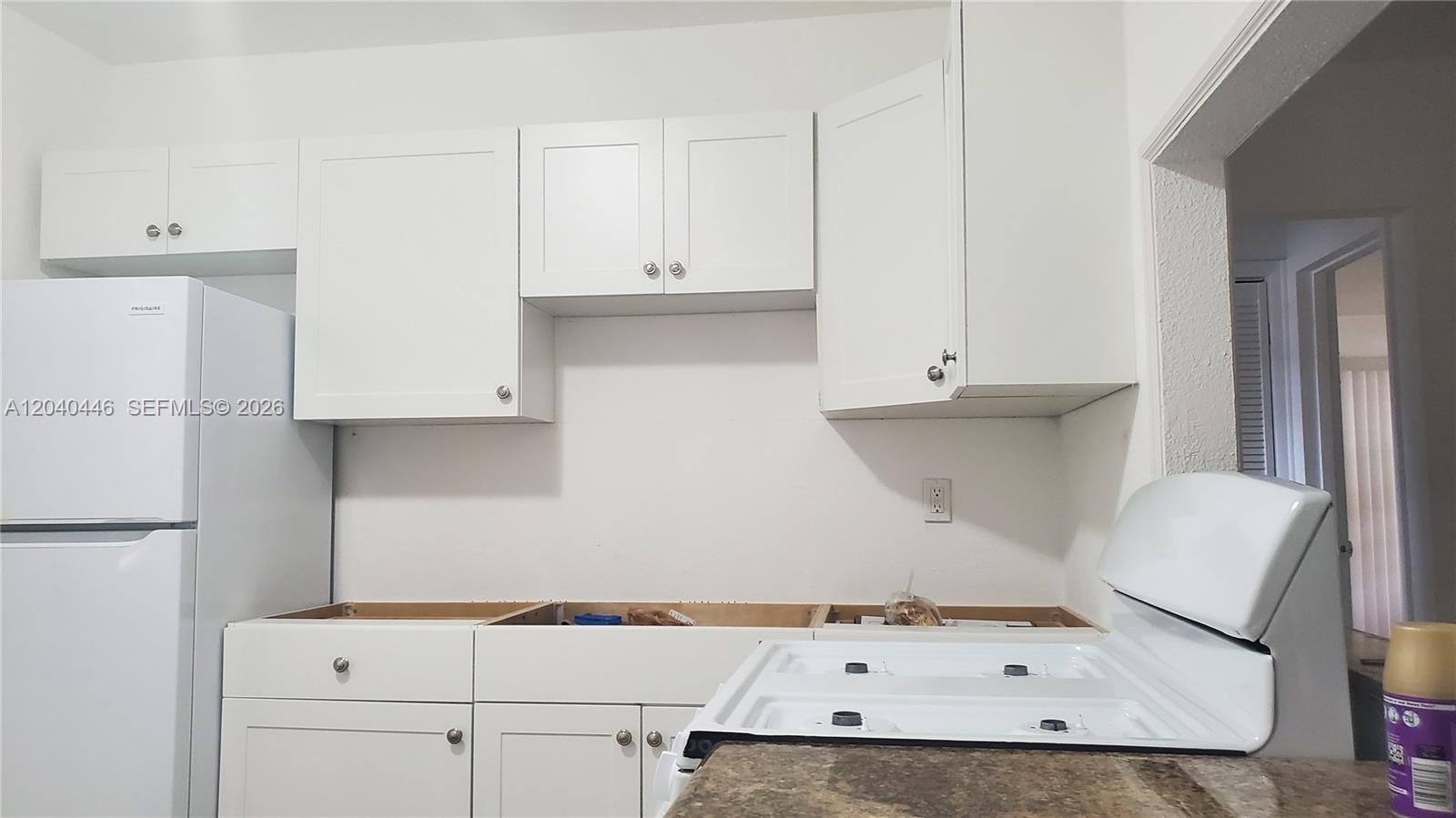 A kitchen features white cabinets, a white refrigerator, and a stove with a missing countertop — 905 SW 4th Ter, Hallandale Beach FL 33009, HALLANDALE BEACH, FL