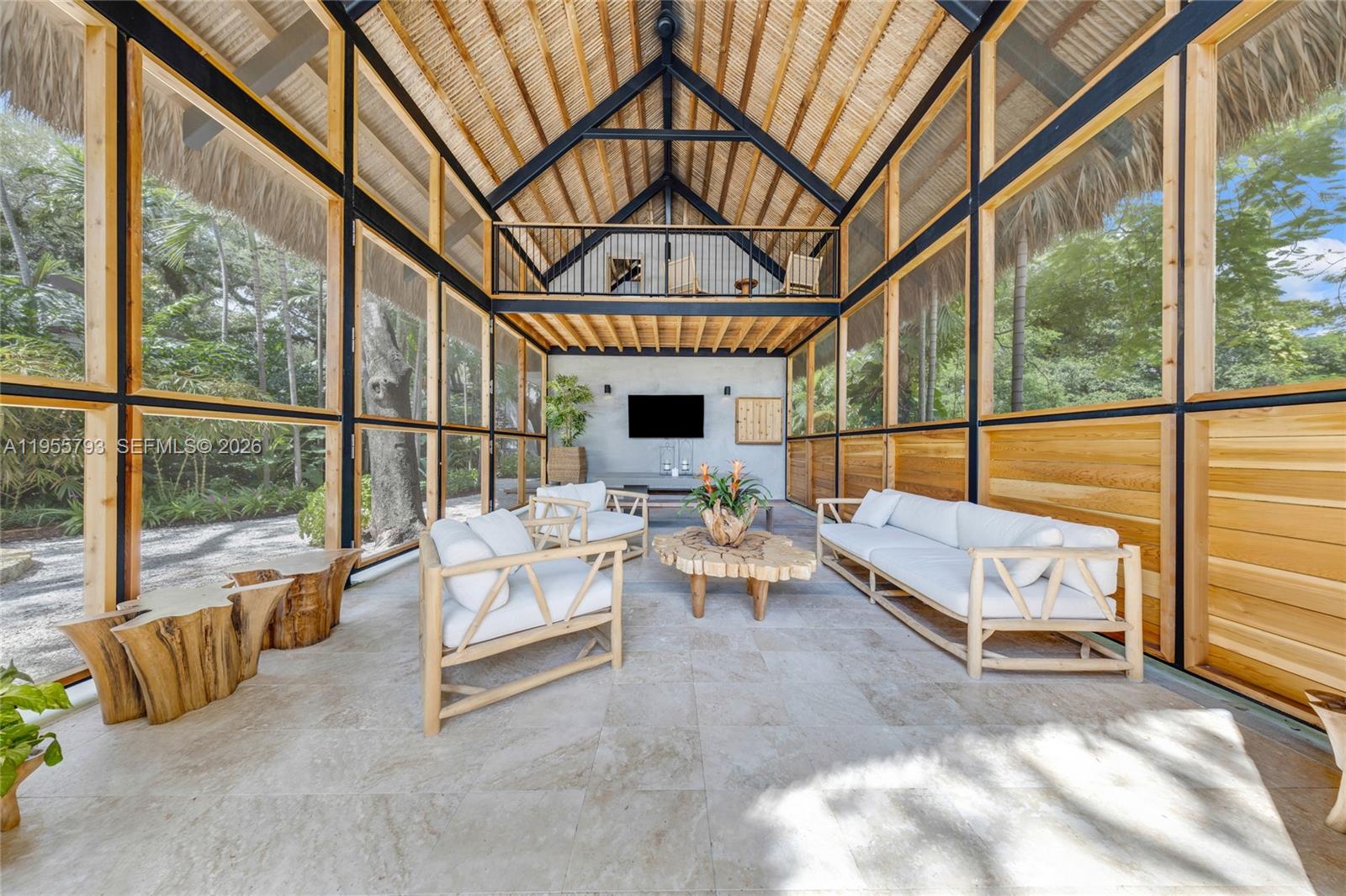 A screened-in outdoor living space features a vaulted thatched roof, stone flooring, and wooden furniture — 1000 NW 9th Ct, Miami FL 33136, MIAMI, FL