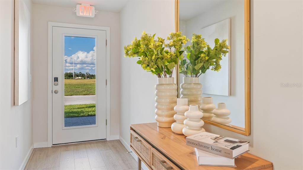 A bright entryway features a wooden console table, decorative vases, and a glass-paneled door — 5192 SCHUBERT TRAIL, NORTH PORT, FL
