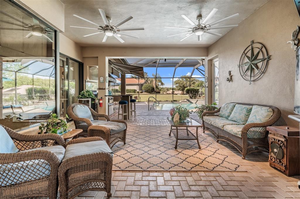 A covered patio features wicker furniture, ceiling fans, a patterned rug, and a pool view — 34115 AMERICANA AVENUE, DADE CITY, FL