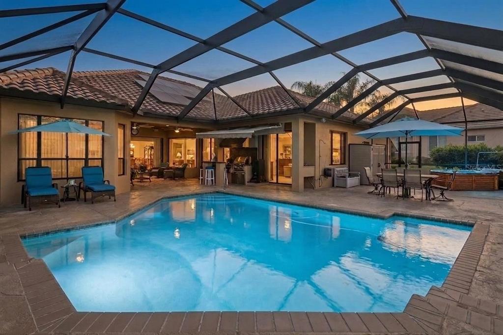 A swimming pool with a screened-in lanai, outdoor dining area, and a built-in grill — 34115 AMERICANA AVENUE, DADE CITY, FL
