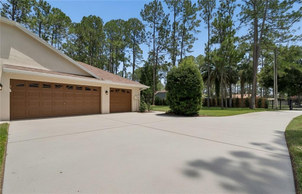 A beige house with a two-car garage and a large concrete driveway under a blue sky — 18811 VICTOR MANUEL DRIVE, LUTZ, FL