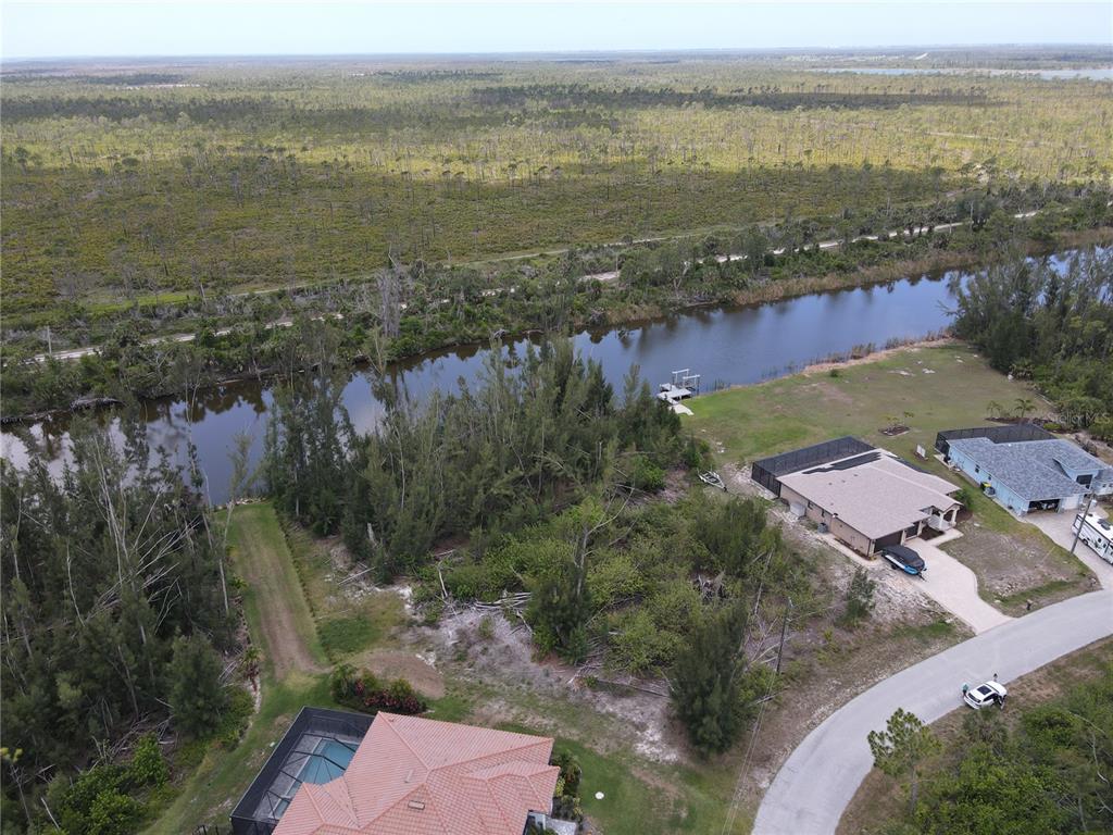 An aerial view shows a canal-front property with two houses, a dock, and surrounding vegetation — 10662 KEARSARGE CIRCLE, PORT CHARLOTTE, FL
