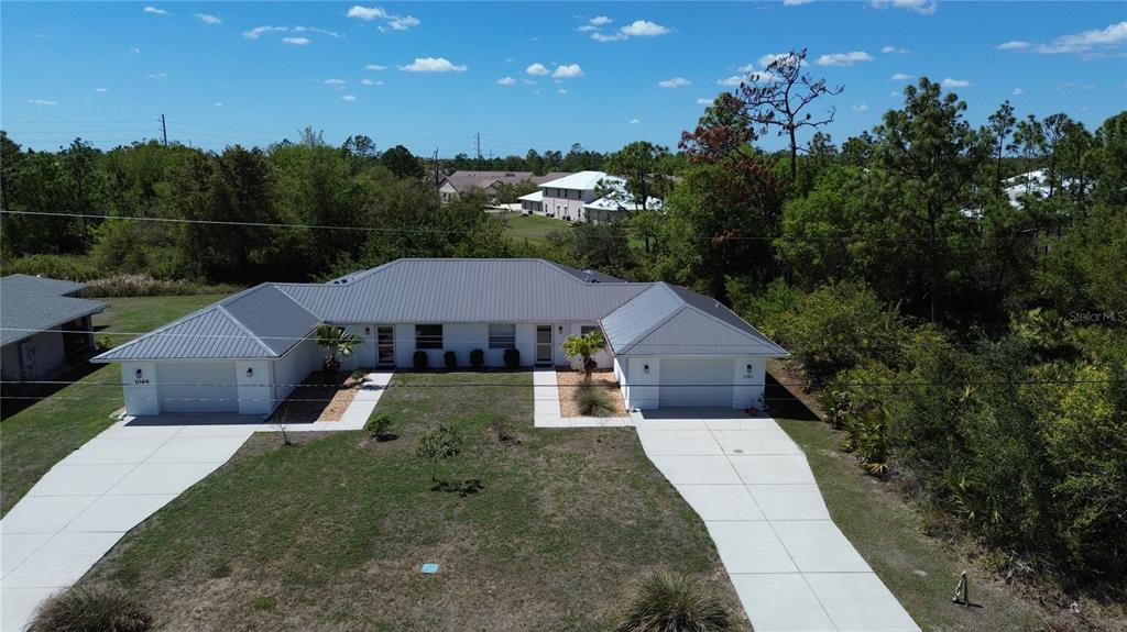 An aerial view of a single-story duplex with a metal roof and two concrete driveways — 1061+1065 NOMAD ROAD, PUNTA GORDA, FL