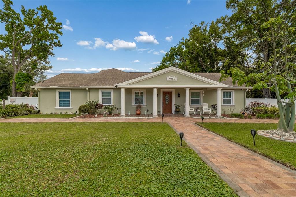 A single-story house with a covered front porch, columns, and a paved walkway — 9406 W FLORA STREET, TAMPA, FL
