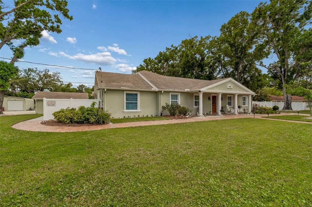 A single-story house with a light green exterior, a covered porch, and a paved walkway — 9406 W FLORA STREET, TAMPA, FL